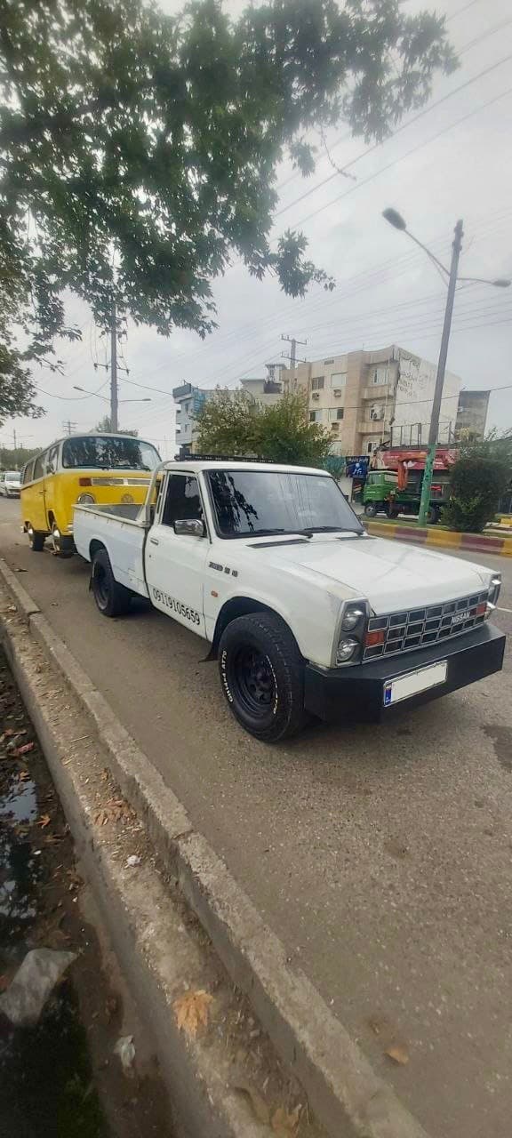 White pickup truck parked on a street with a vintage yellow Volkswagen van behind it.